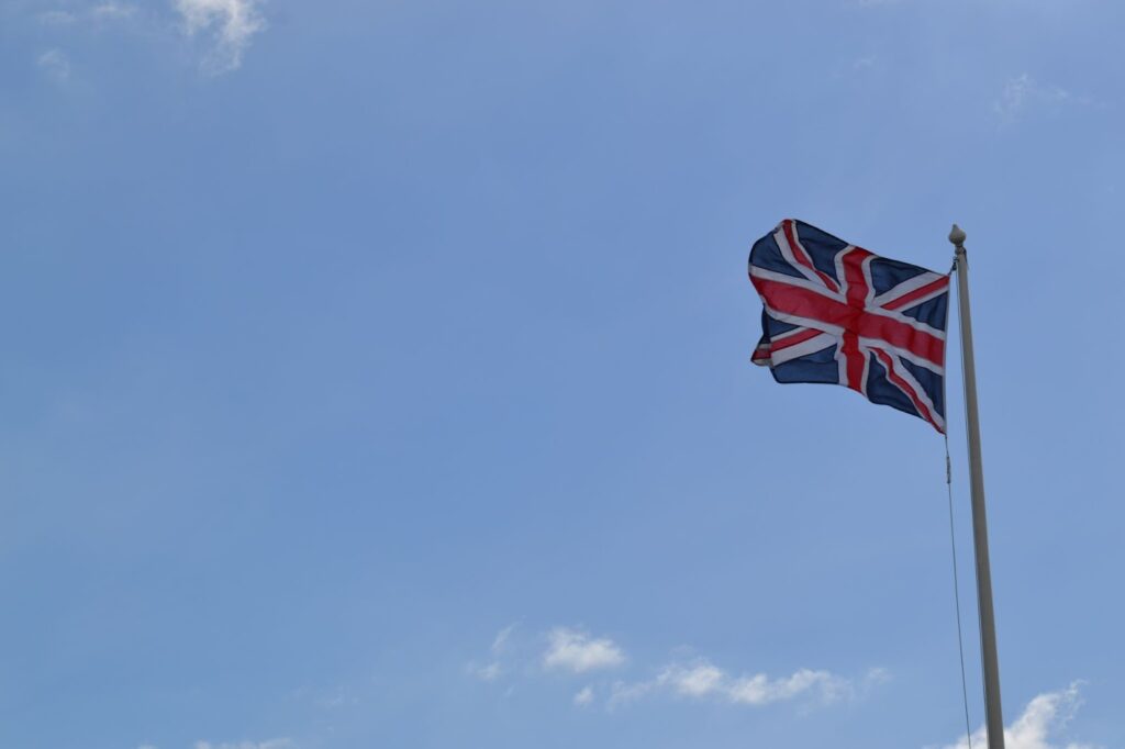 the flag of Great Britain on a pole under the cloudy sky